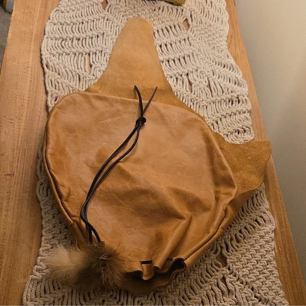 Handcrafted tan leather drawstring pouch featuring a soft fur pom-pom